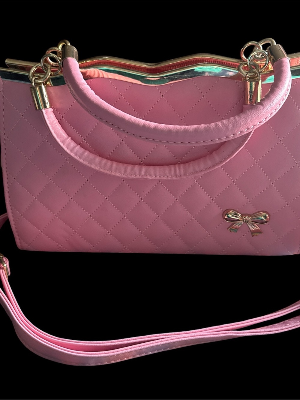 Pink quilted handbag with gold accents.